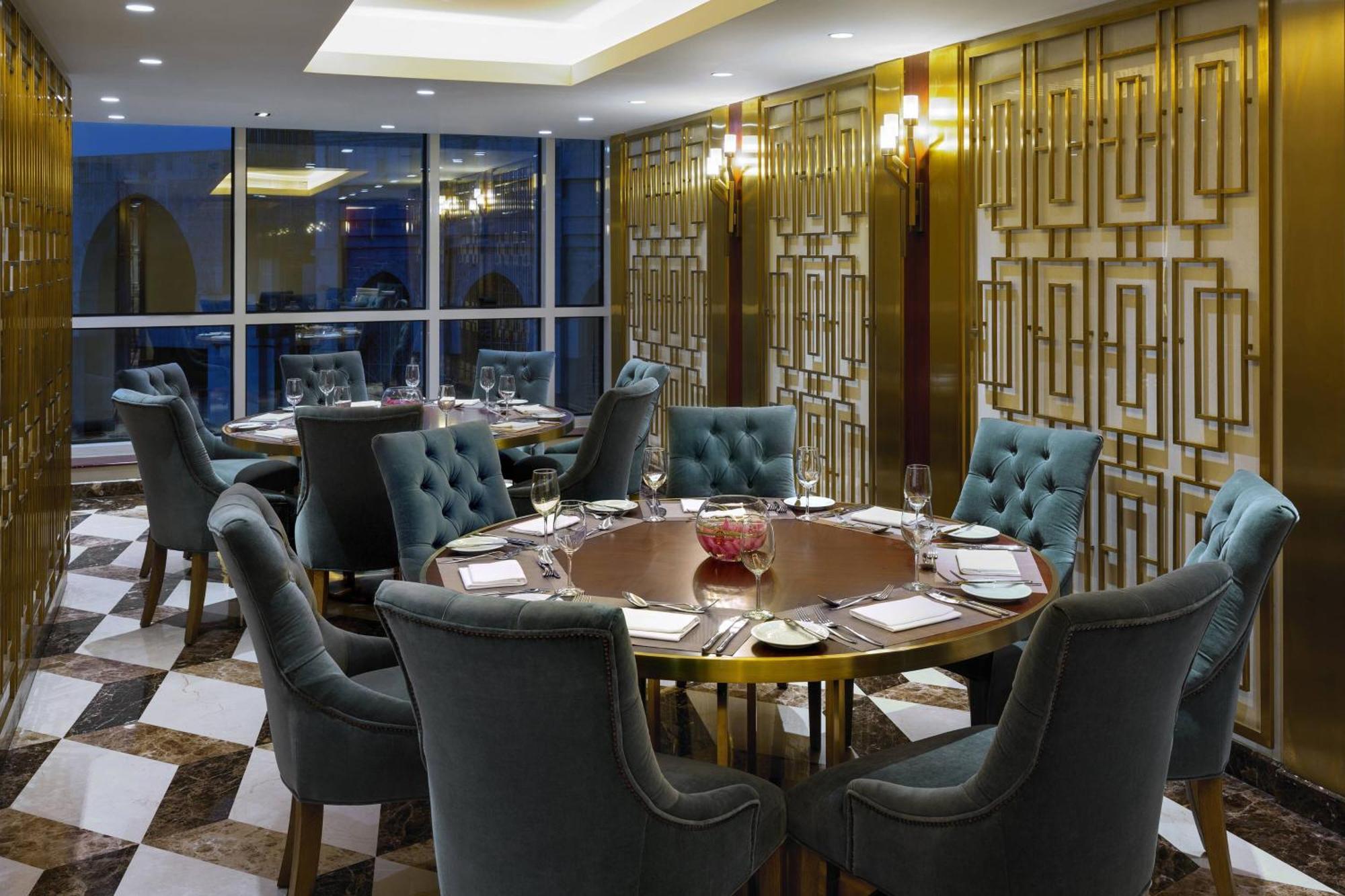 Sheraton Makkah Jabal Al Kaaba Hotel Мекка Экстерьер фото The photo shows an elegant dining room with a sophisticated ambiance. It features a round wooden table at the center, surrounded by plush chairs upholstered in a soft, teal fabric. The room has a stylish décor, highlighted by a geometrically patterne